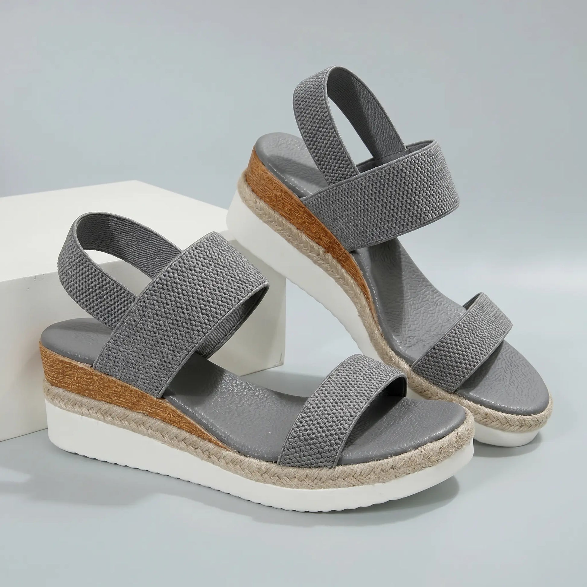 Pair of grey textured mesh espadrille wedge sandals with peep-toe, elastic straps, and layered platform with jute rope detail.