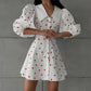Woman wearing a white cotton linen blend A-line midi dress with a red heart print, featuring dramatic puff sleeves and a pointed collar, shown from the front.