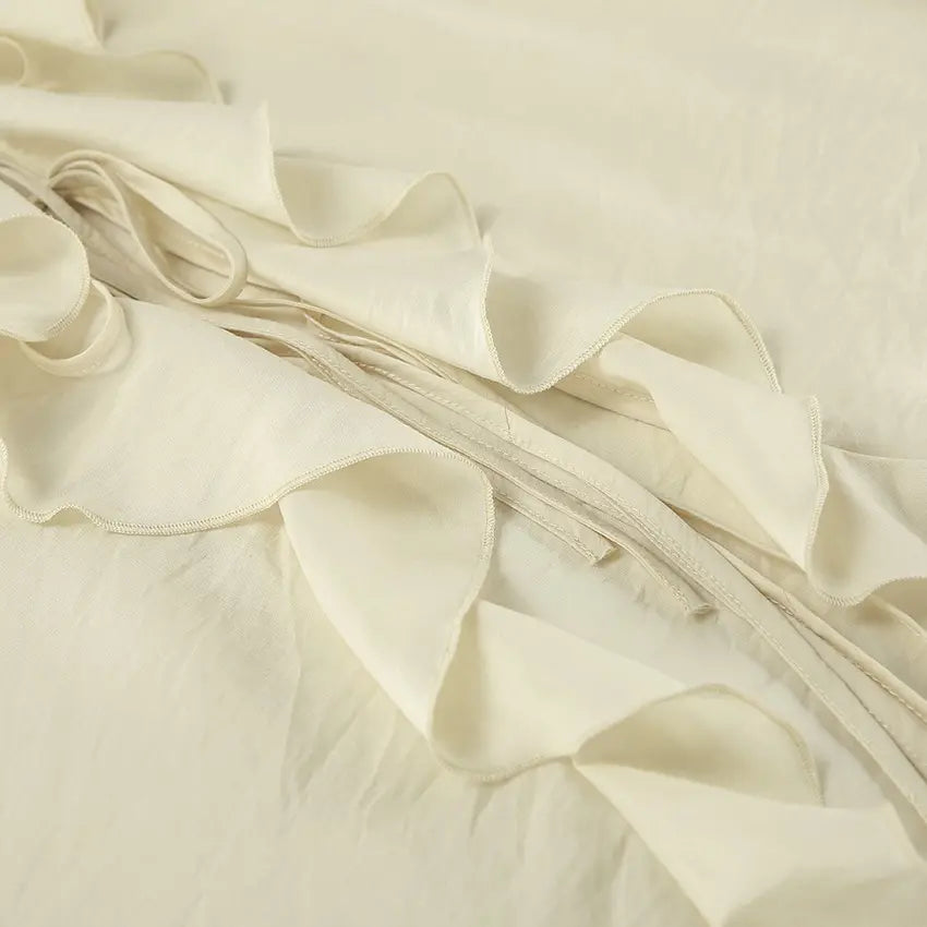 Close-up view of a cream ivory bohemian ruffle set showcasing tiered ruffles, delicate tie strings, and lightweight woven fabric texture.