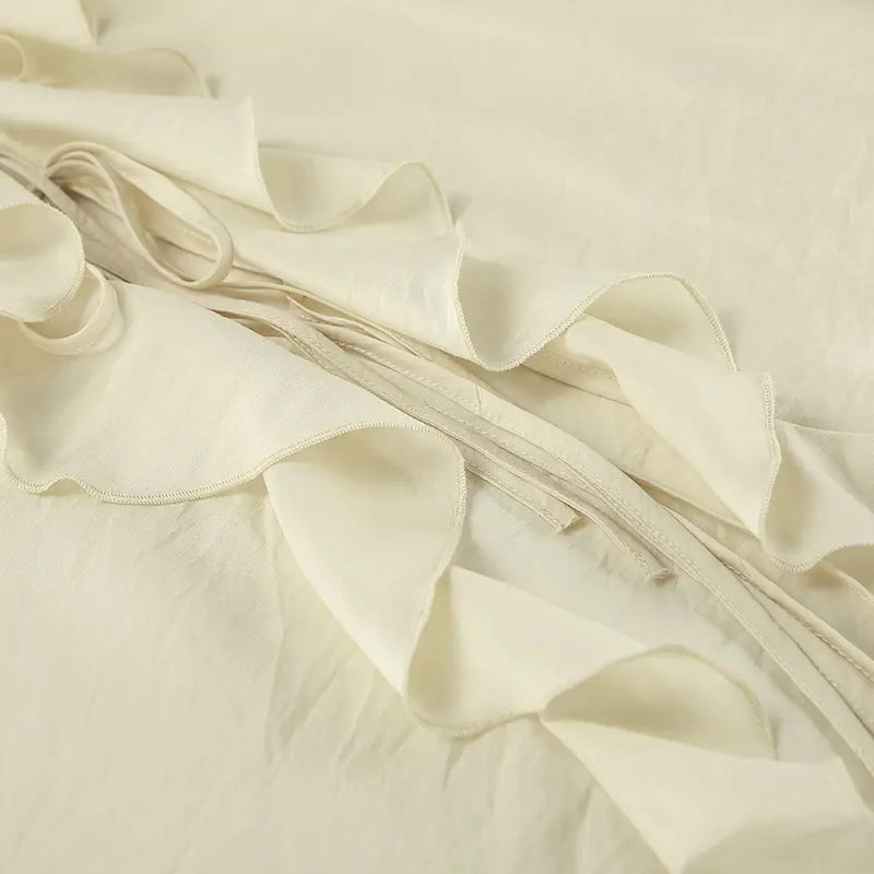 Close-up view of a cream ivory bohemian ruffle set showcasing tiered ruffles, delicate tie strings, and lightweight woven fabric texture.