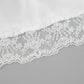 Close-up view of ivory satin fabric with delicate white floral lace trim along the hem, showcasing intricate embroidery and scalloped edging.