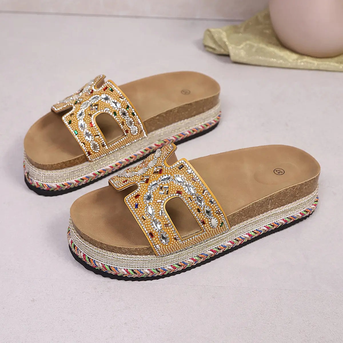 Jelani embellished platform slide sandals in gold with intricate bead and rhinestone details, featuring a cork footbed and woven midsole, shown from a three-quarter angle.