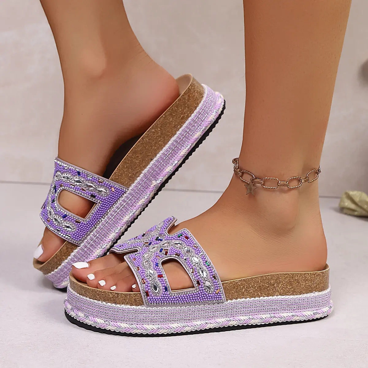 Jelani embellished platform slide sandals in lavender, worn on a woman's feet, showcasing intricate bead and rhinestone detailing on the straps and a cork sole with woven midsole.