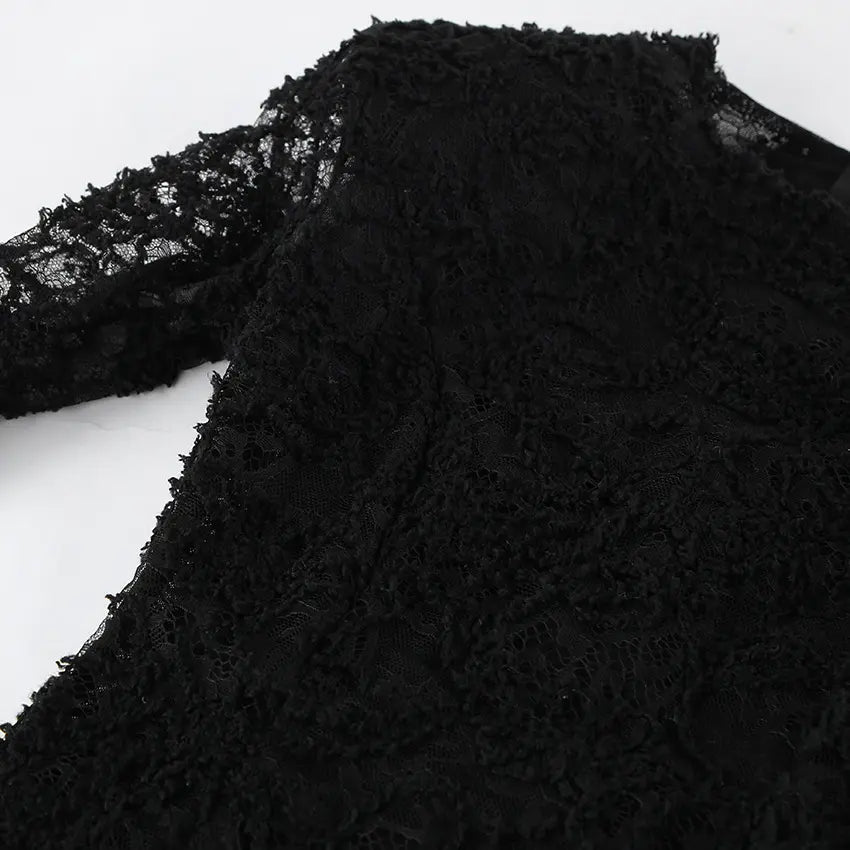 Close-up view of a black Kaelen lace mini dress, showcasing the intricate floral lace texture on the long sleeve and shoulder.