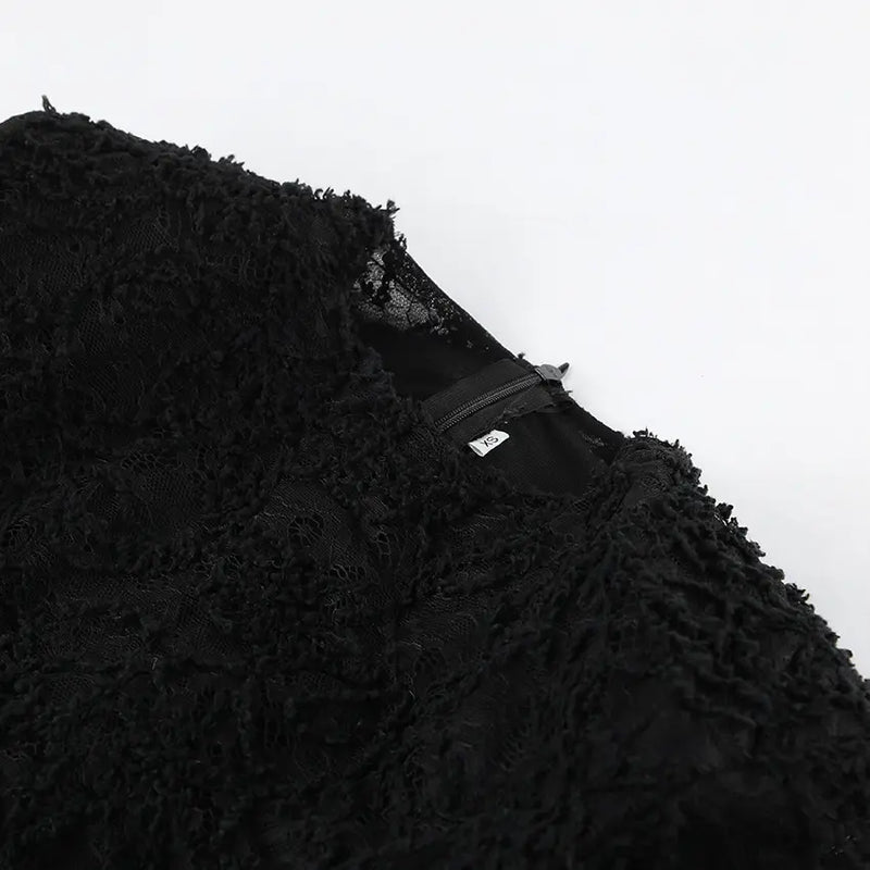 Close-up view of a black Kaelen dress, showcasing the intricate floral lace texture, plush faux fur material, and a visible zipper with size label XS.