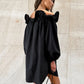 Black Kaelen off-shoulder cotton mini dress with voluminous balloon sleeves shown on a model from a three-quarter view against a textured studio background.