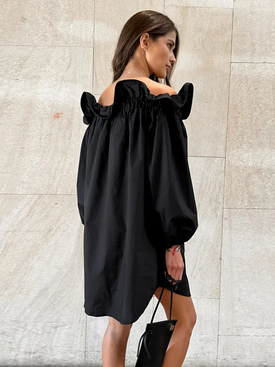 Black Kaelen off-shoulder cotton mini dress with voluminous balloon sleeves shown on a model from a three-quarter view against a textured studio background.