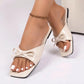 Kaelen Chic Bow Flat Sandals in Soft Cream, featuring an open square toe, glossy patent PU upper with a prominent sculpted bow, and a flat black rubber sole, shown on a model's foot.