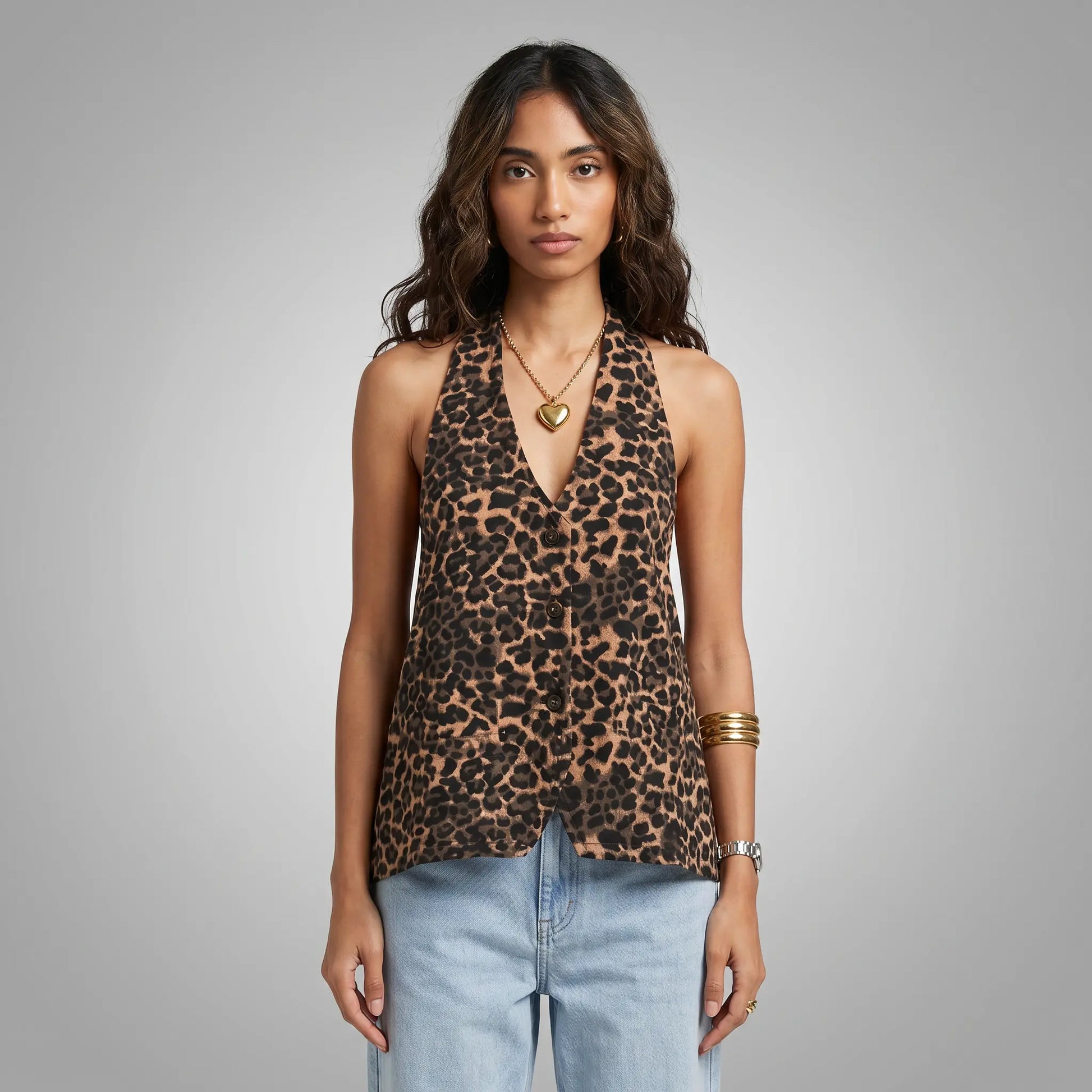 Front view of a woman wearing a Kaelen leopard print halter neck top with a deep V-neck and subtle front buttons, paired with light blue jeans.