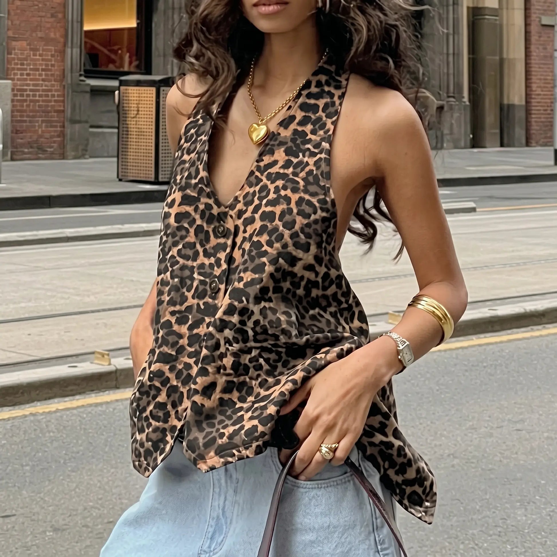Kaelen leopard print halter top with deep V-neck and open back, worn by a model on a city street with denim jeans.
