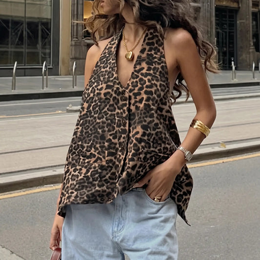 Model wears a bohemian leopard print halter neck top with a deep V-neck and open back, styled with light blue denim jeans on a city street.