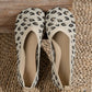 A pair of women's Kaelen knit ballet flats featuring a classic leopard print in black and brown on a creamy off-white base. These slip-on shoes have a round toe and flat sole, presented on a textured woven mat.