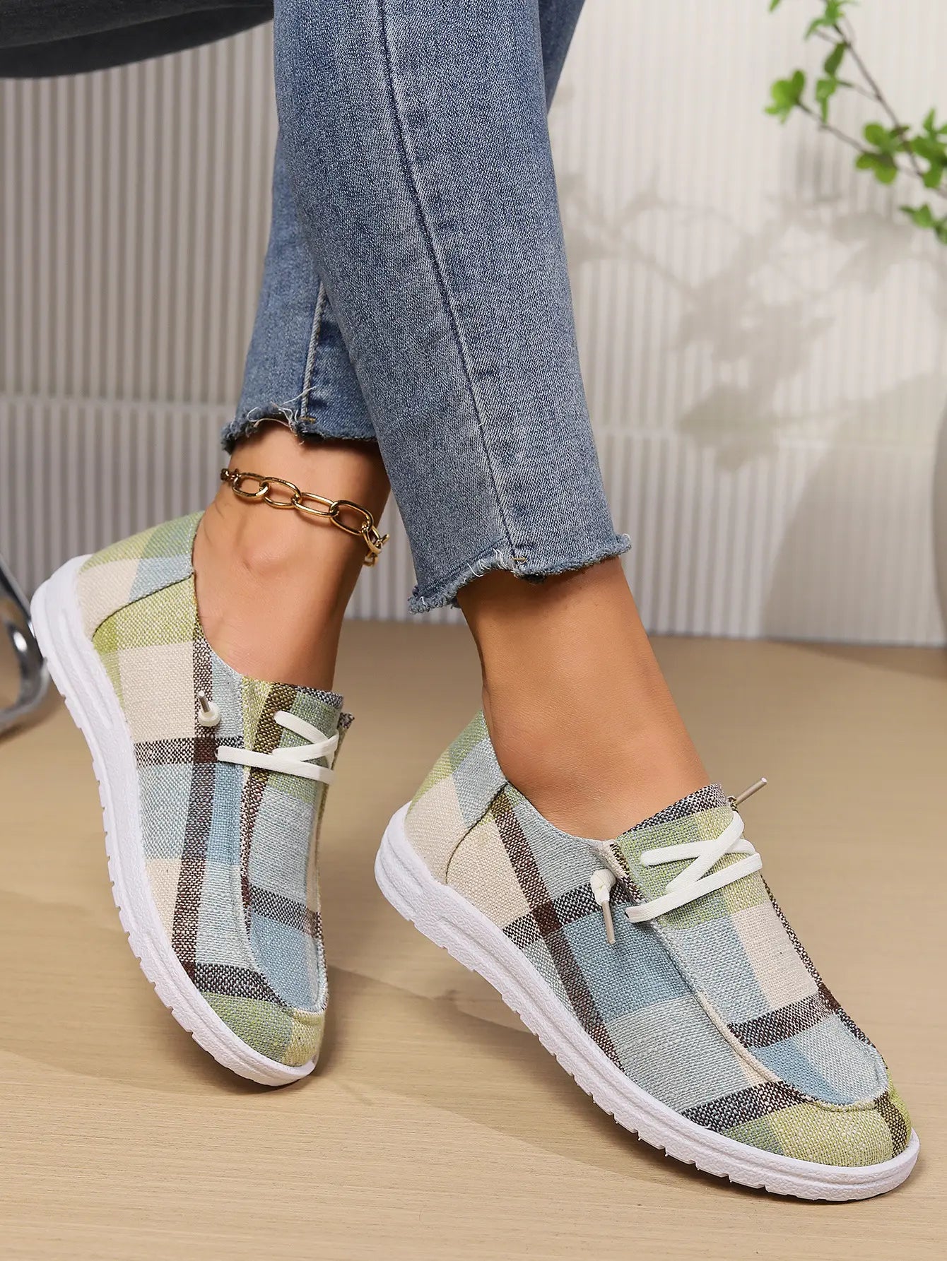 Kaelen women's plaid canvas loafers with decorative white laces and white rubber soles, shown on feet with distressed denim jeans.
