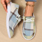 Kaelen comfortable canvas loafers in a blue, green, and beige plaid pattern, styled on feet with white laces and white rubber soles, complemented by a gold anklet on a wooden floor.