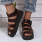 Platform gladiator sandals in a rich burgundy faux leather with a chunky black sole and black buckle strap, shown on a person's feet with cuffed denim jeans.