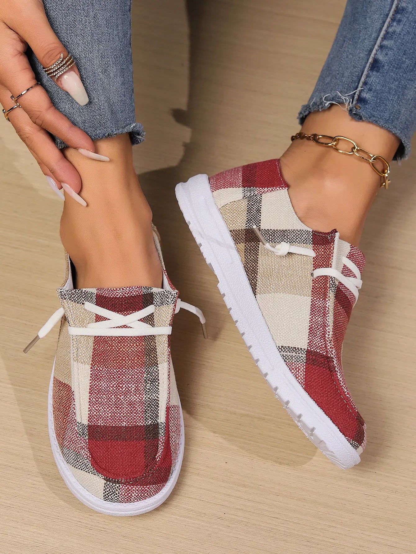 Kaelen women's plaid canvas slip-on loafers in warm red plaid, worn with blue jeans and featuring white decorative laces and a white rubber sole.