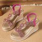 A pair of Kaelen embellished wedge sandals in shimmering rose gold with gold accents, featuring rhinestone and bead details on wavy straps and an elasticated slingback. The wedge sole has a woven espadrille-style texture and metallic band.