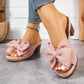 Rose pink Kaelen slip-on sandals with a large textured fabric bow and fish-mouth peep-toe, worn by a model with blue denim jeans and a turquoise anklet. Features a 7cm wood-grain block heel and platform sole.