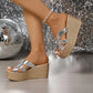 Women's Kaelen silver cracked metallic espadrille wedge sandals worn with a pearl anklet, showcasing the criss-cross straps and platform sole against a festive disco-themed backdrop.