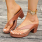 Close-up of tan Kaelen elegant heeled slides with a chunky block heel and platform sole, worn on feet with a decorative floral anklet, resting on a wooden surface.