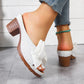 Women's Kaelen white slip-on mule sandals with textured fabric bow detail, fish-mouth peep-toe, and a 7cm wood-grain block heel worn with blue denim jeans and a turquoise anklet.