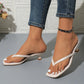 Model's feet wearing white heeled thong sandals with a square toe and sculptural mid-height block heel, paired with blue denim jeans.