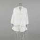 White Kaelen linen-blend two-piece set featuring a loose V-neck blouse with lantern sleeves and ruffled hem shorts, displayed on a mannequin front view.