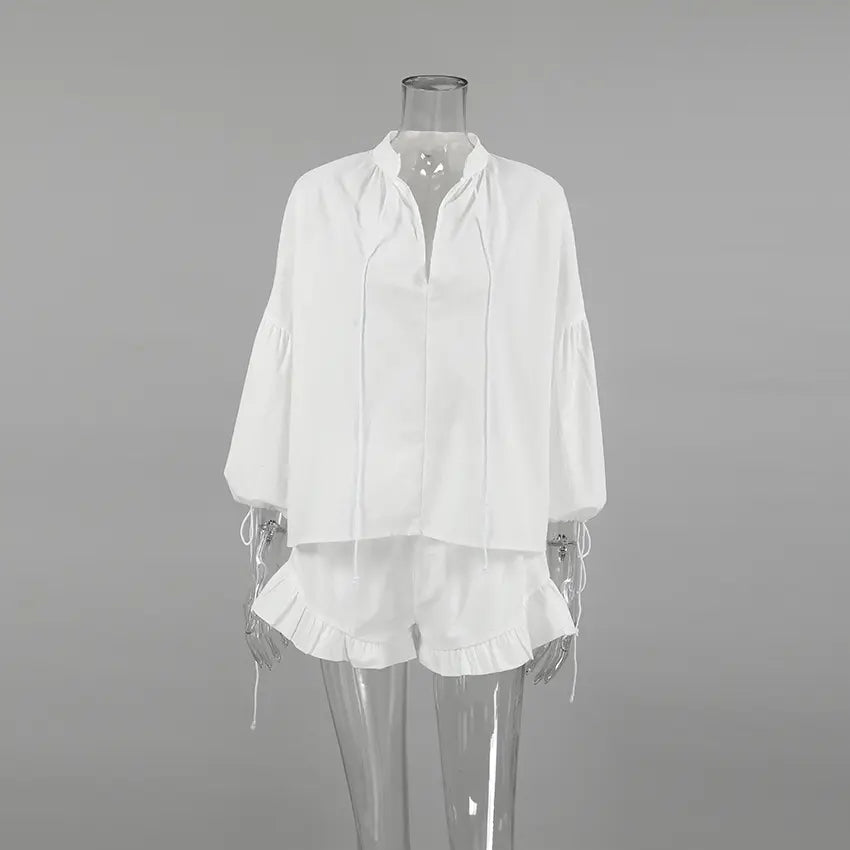 White Kaelen linen-blend two-piece set featuring a loose V-neck blouse with lantern sleeves and ruffled hem shorts, displayed on a mannequin front view.