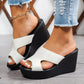 White Kaelen peep-toe wedge sandals with a single strap, styled with ripped denim jeans on a woman's feet, showcasing the comfortable platform heel.
