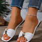 Kaelen white woven flat slide sandals featuring a chic oval gold buckle and square toe, styled with distressed denim jeans.
