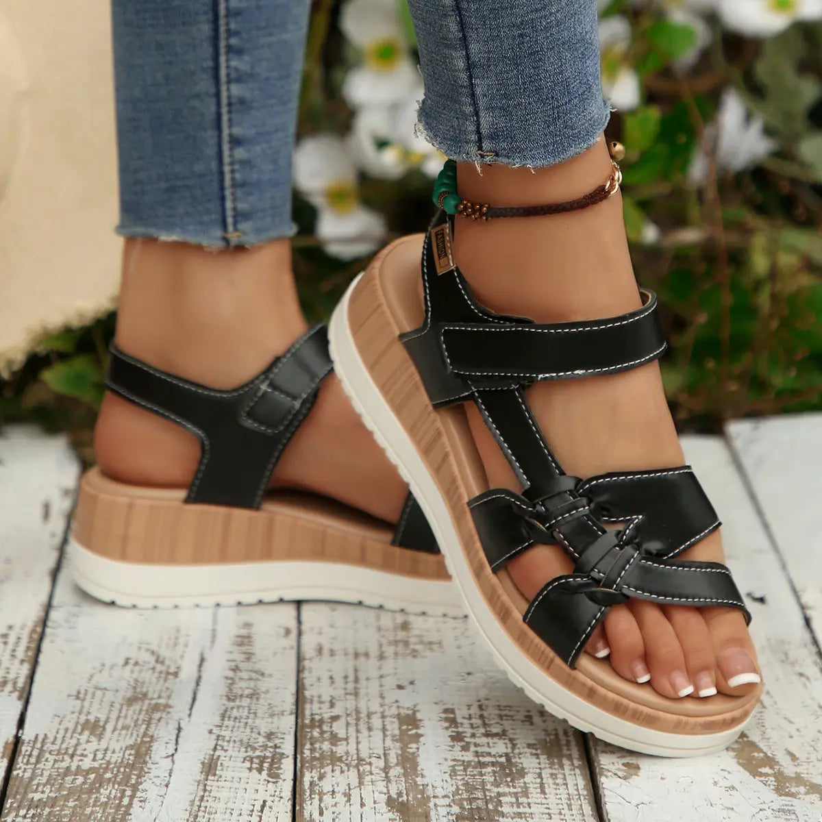 Kaelen women's black flat sandals with adjustable hook-and-loop straps and a bohemian-inspired knot detail on the forefoot strap. These open-toe sandals feature a wood-grain effect platform sole for comfortable summer wear.