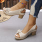 Beige Kaelia peep-toe sandals with chunky block heel and artisanal floral embellishment, shown on a model's feet with perforated detailing and adjustable ankle strap.