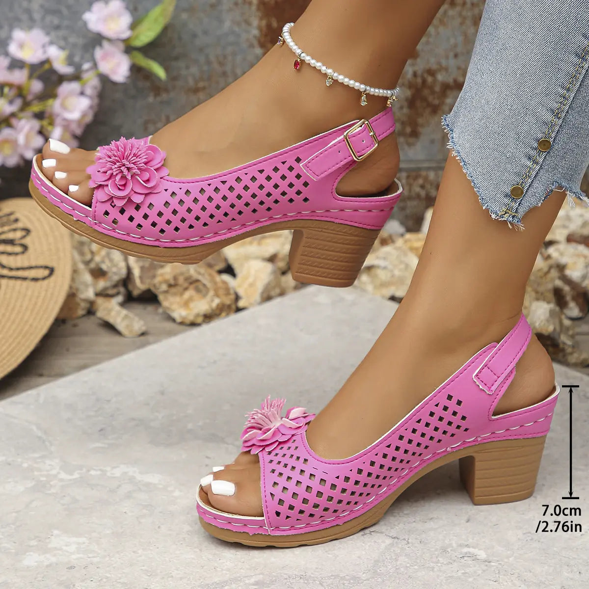 Pink Kaelia peep-toe chunky heel sandals with floral embellishment and perforated square pattern, shown on a model's feet with jeans.