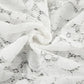 Close-up view of intricate white floral lace jacquard fabric on Kaelia flared trousers, showcasing detailed texture and delicate patterns.