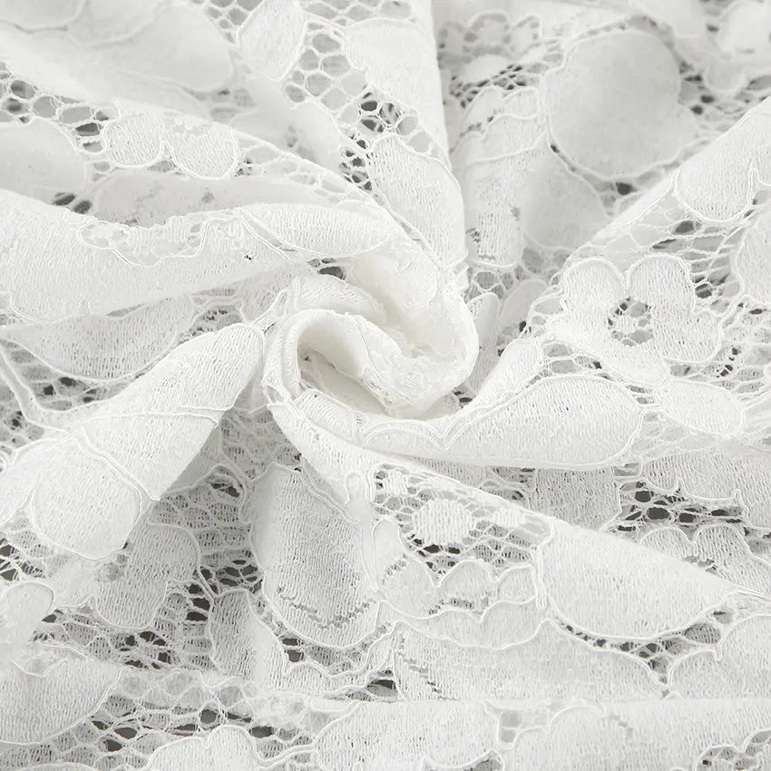 Close-up view of intricate white floral lace jacquard fabric on Kaelia flared trousers, showcasing detailed texture and delicate patterns.