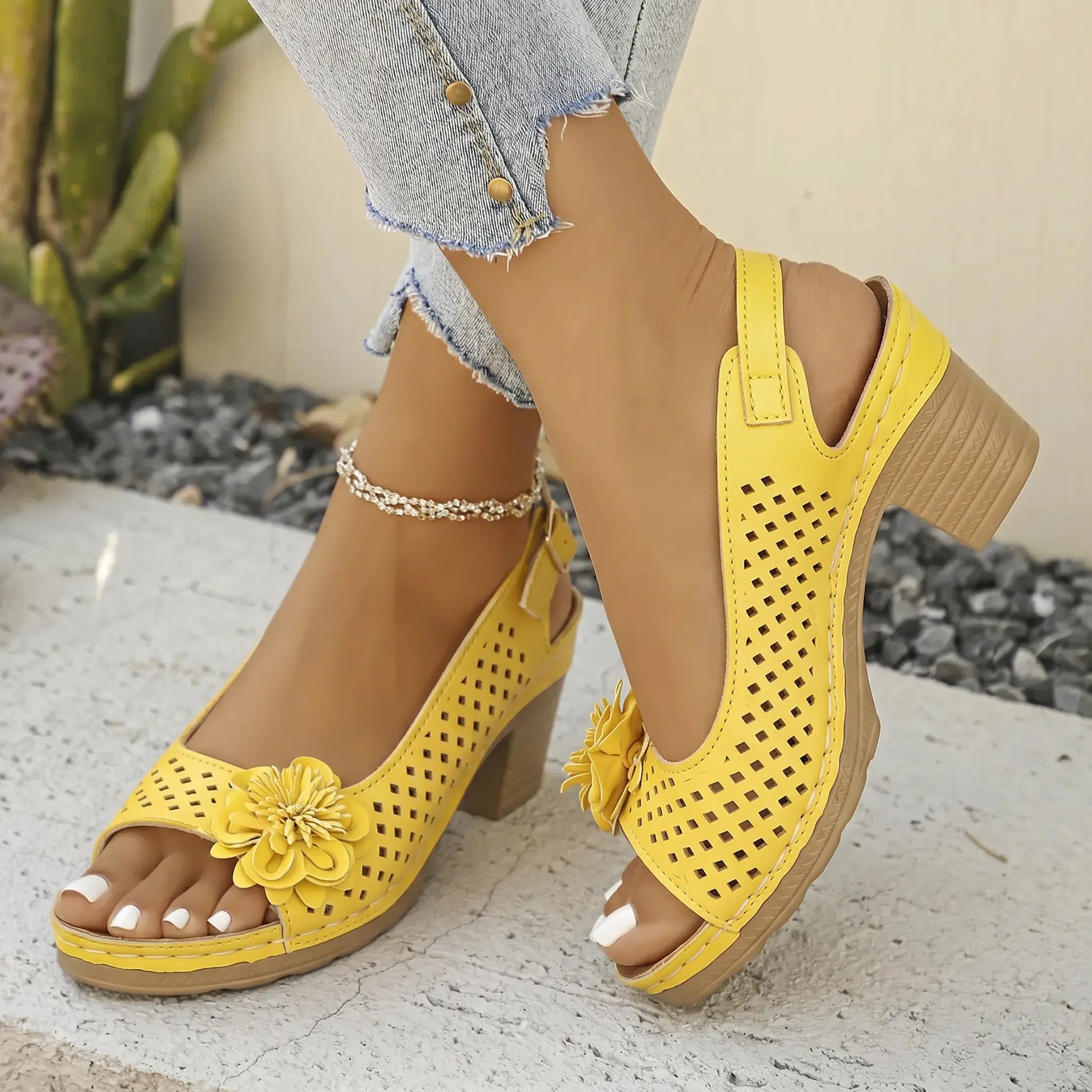 Sunny Marigold Kaelia chunky heel sandals with floral embellishment and perforated peep-toe design, shown on a model's feet with denim jeans.
