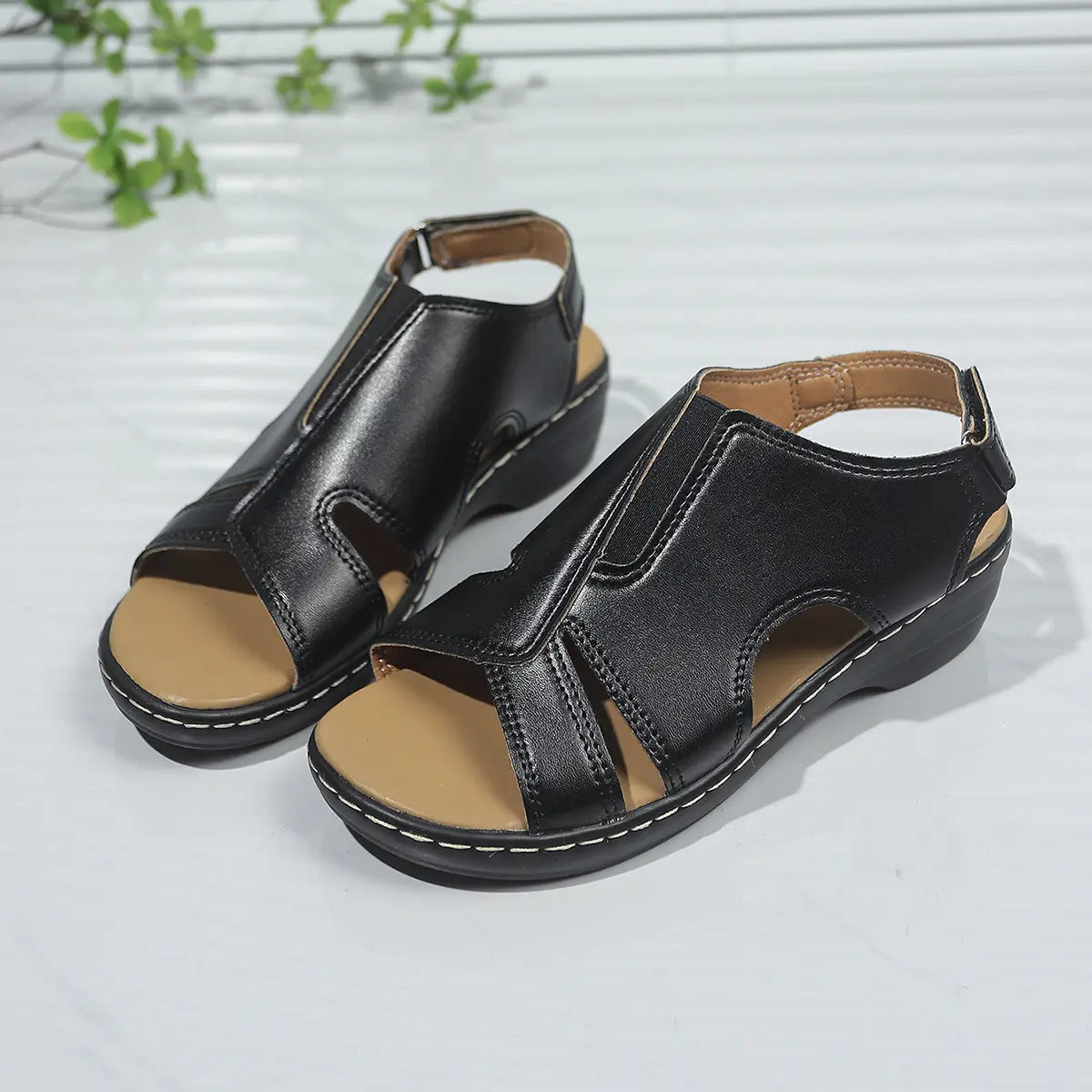 Kaelin black faux leather platform wedge sandals featuring a peep-toe design, adjustable ankle strap, and contrasting white stitching.