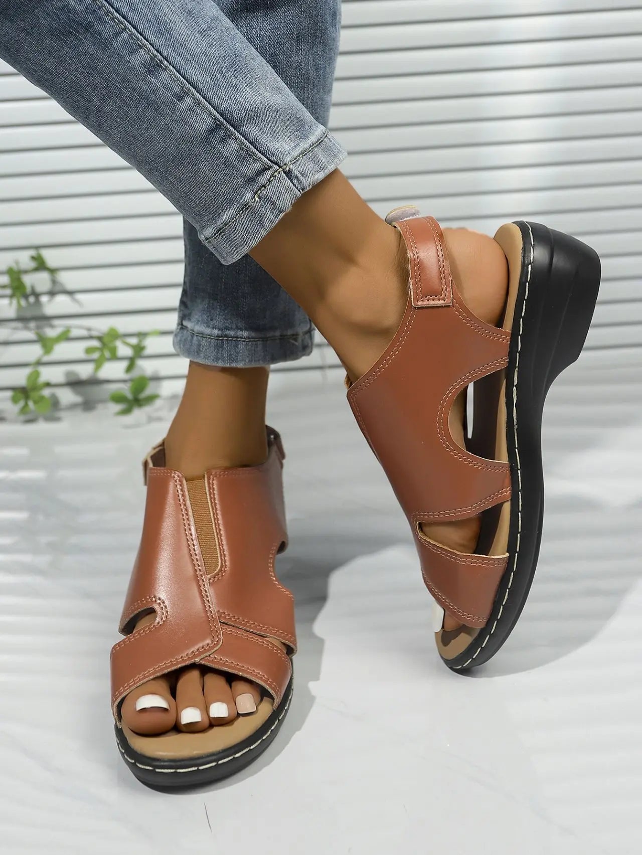 Front view of brown faux leather Kaelin platform wedge sandals worn by a model, showcasing the peep-toe design, adjustable ankle strap, and white contrast stitching on the wedge sole.