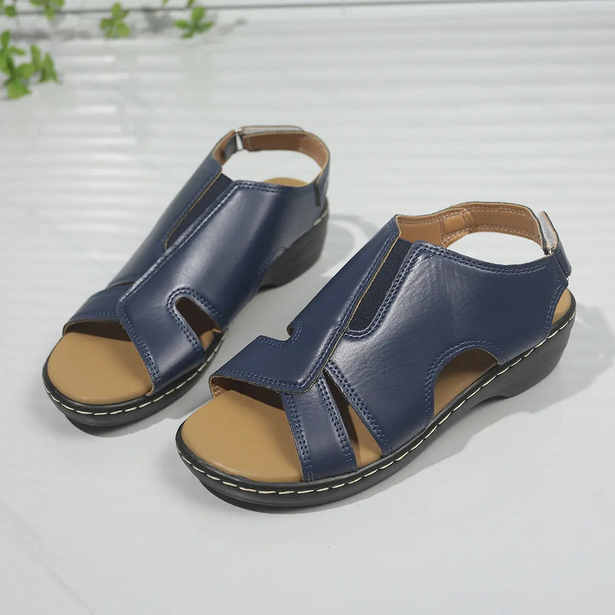 Navy blue Kaelin platform wedge sandals with adjustable ankle strap and peep-toe design, crafted from smooth faux leather and featuring white contrast stitching.