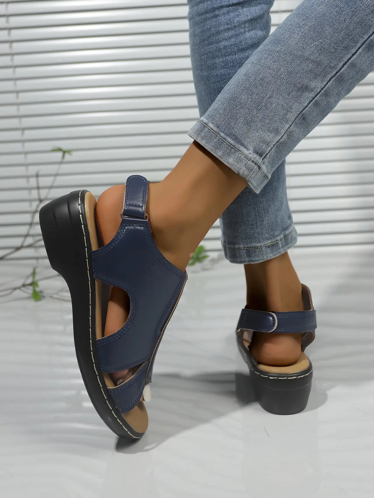 Kaelin navy blue faux leather platform wedge sandals with adjustable ankle strap and peep-toe design, shown on a woman wearing denim jeans.
