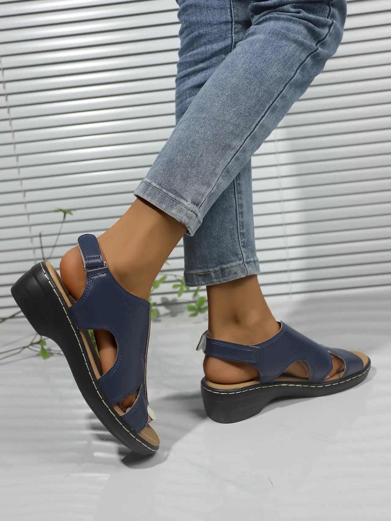Women's navy blue Kaelin platform wedge sandals with peep-toe, cut-out vamp strap, and adjustable ankle strap, shown worn with jeans.
