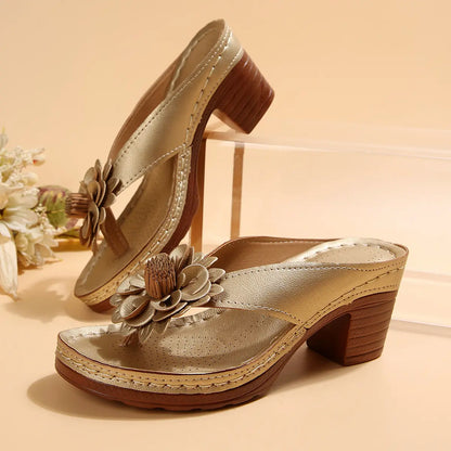 Kaelis gold floral platform sandals featuring a 3D flower embellishment on a single wide strap and a stacked block heel with a wood-effect finish.