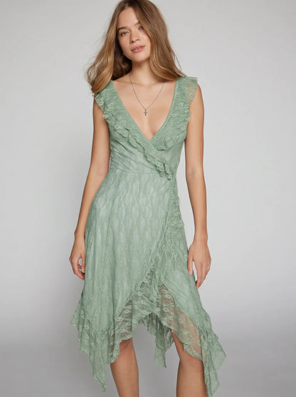 Misty Sage Green Kaelis romantic boho chic midi dress featuring a V-neck with cascading ruffles and an asymmetrical tiered ruffle hem, shown on a model.