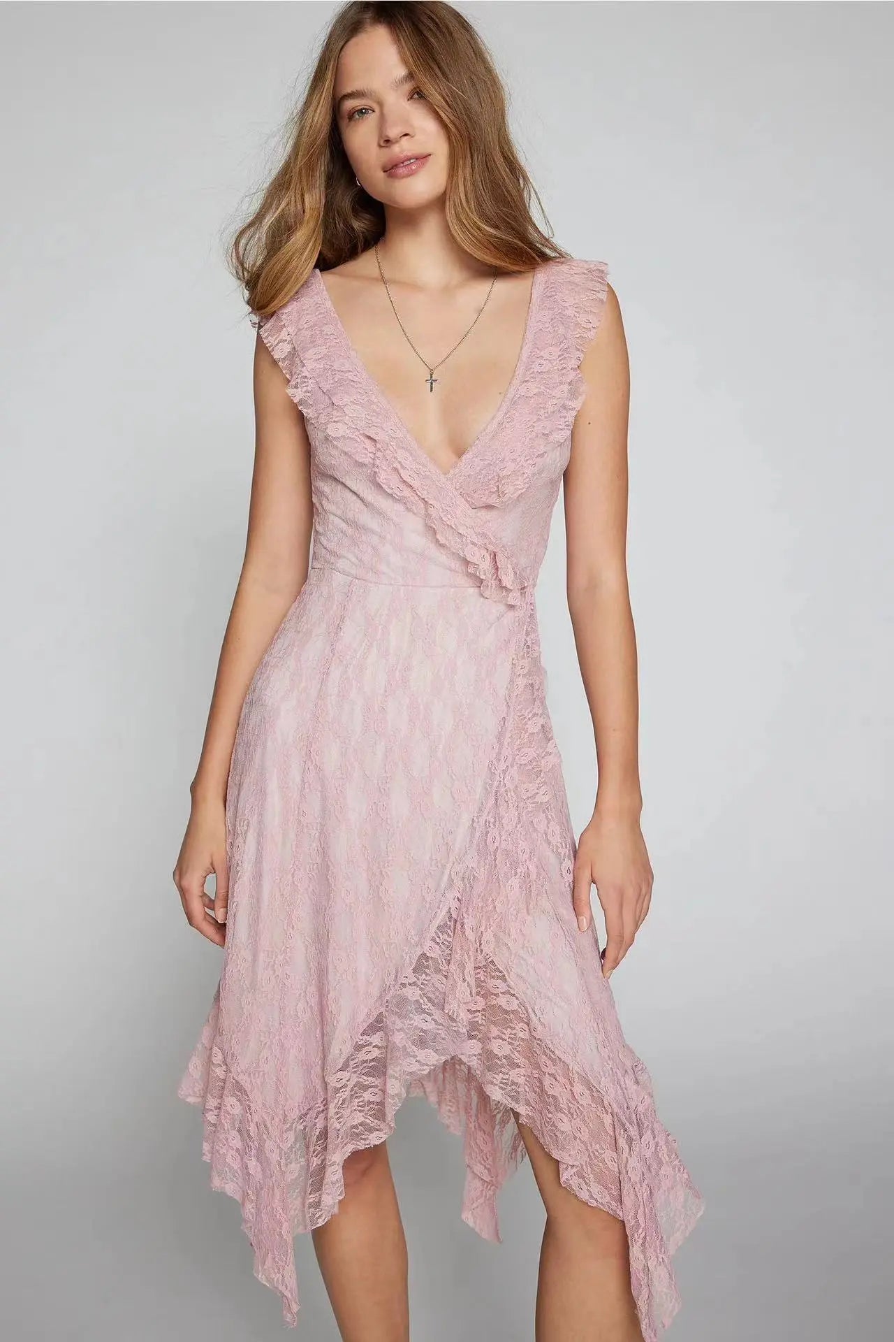 Kaelis romantic midi boho chic lace V-neck dress in soft pink, showcasing its flowing asymmetrical tiered ruffle hem and sleeveless design worn by a model.