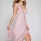 This Kaelis lace V-neck midi dress in soft pink features a flowing asymmetrical ruffled hem and delicate ruffled shoulder straps, showcased on a model from a three-quarter view.