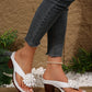 Kaelis white floral platform sandals worn by a model, showcasing the 3D flower embellishment and chunky block heel with distressed denim jeans and a pearl anklet.