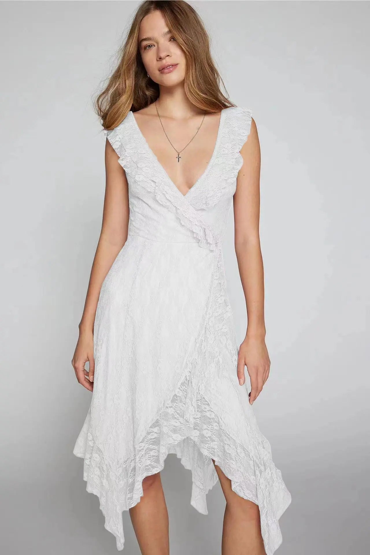 Kaelis romantic white lace V-neck midi dress with cascading ruffles and an asymmetrical tiered ruffle hem, shown on a model with a slight three-quarter view.
