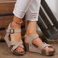 Women's beige Kaelix wedge sandals with studded criss-cross straps and a speckled brown wedge sole, styled on a model's legs wearing ripped white jeans and a colorful anklet on a wooden floor.