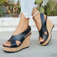 Kaelo black faux leather criss-cross strap wedge sandals with a multi-colored speckled cork platform and heel, worn by a model on a concrete path with cacti in the background.