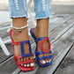 Kaelo women's asymmetrical color-block flat slide sandals in red and blue, featuring geometric and circular cut-outs, shown on feet with ripped denim jeans.